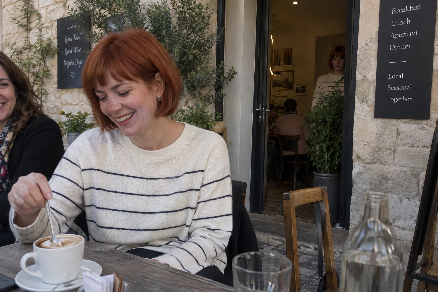 A woman enjoying a cafe with an identical version of her watching from the background.