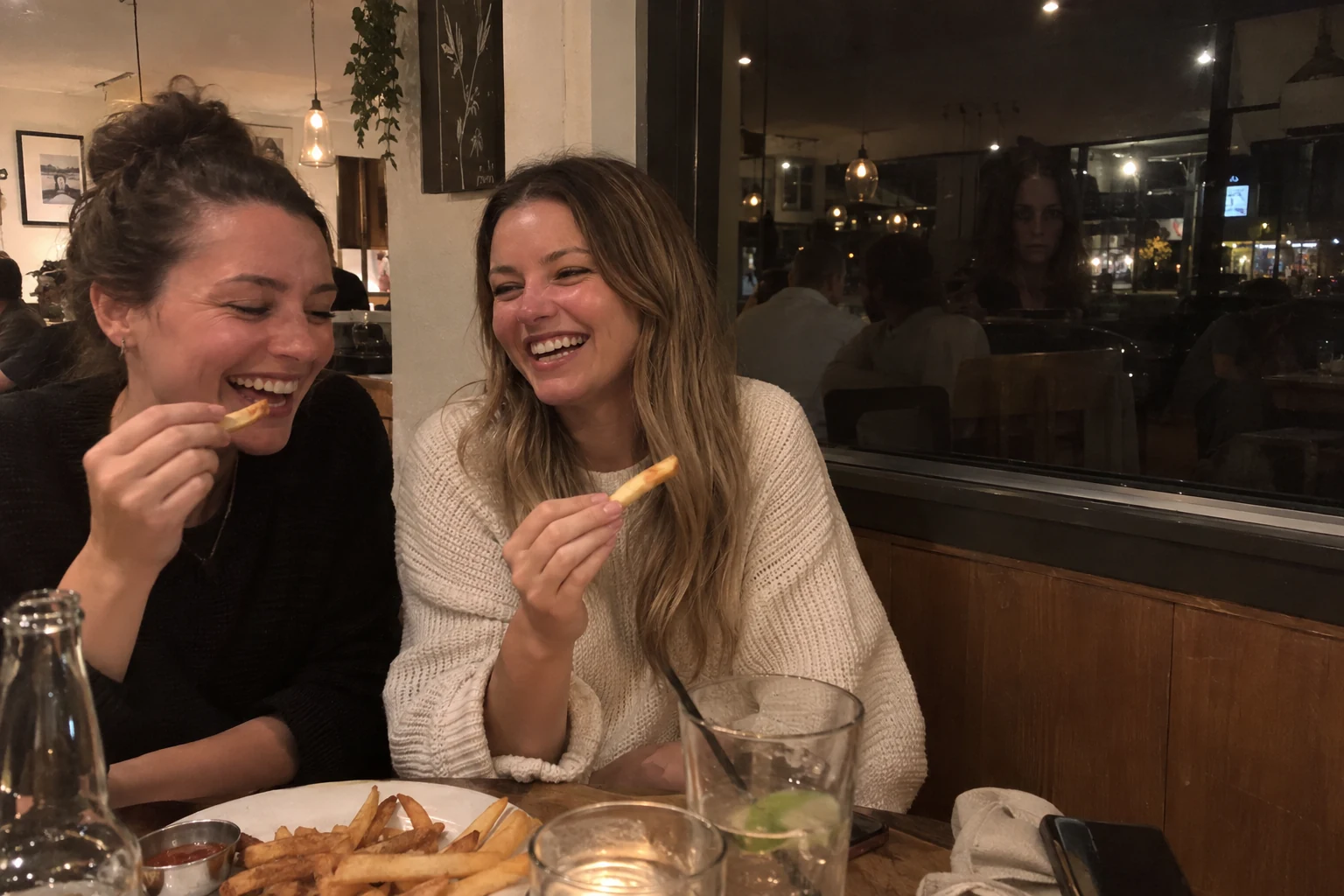 Friends eating in a restaurant with an extra woman's face reflected in the window behind them.
